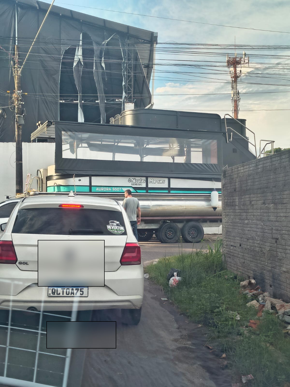 Lancha pontoon 'AURORA 900T' (Nicolas Marques) sobre caminhão estacionado na via lateral do galpão de destino. Imagem registrada por populares durante o trajeto.