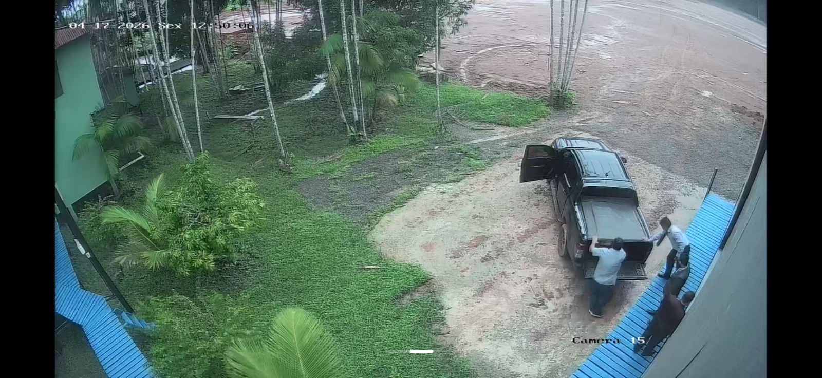 Câmera 15 — chegada ao pátio externo da Elinsa antes da ação na marina. Caminhonete preta com porta-malas aberto e dois homens manuseando o vão de carga.